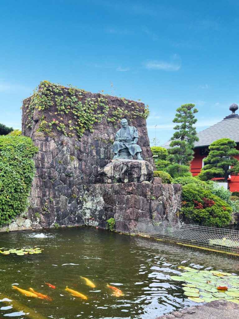 次郎長銅像の背後の石垣と池（梅蔭禅寺境内）