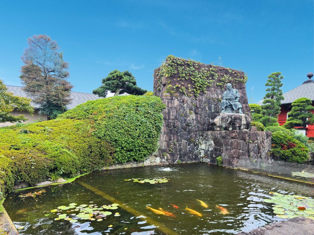 次郎長銅像の背後の石垣と池(梅蔭禅寺境内)